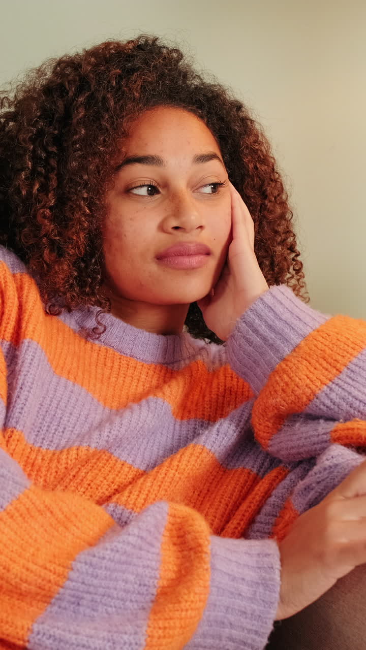Thoughtful Young Woman with Curly Hair Resting Her Head on Hand