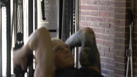 muscly man in home gym exercising blurry dumbbell tricep skull crusher