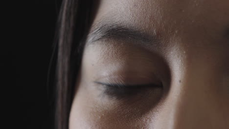 asian-woman-eye-blinking-looking-at-camera-on-black-background-close-up