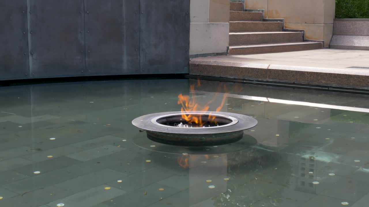 Slow motion close-up of the Eternal Flame fire pit in water pond at the Australian War Memorial Museum building Canberra ACT Australia tourism remembrance landmark architecture