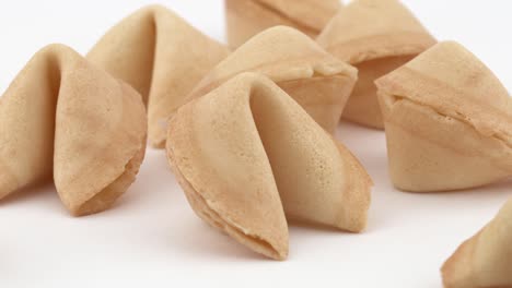 primer plano de una tradicional galleta de la fortuna china que gira lentamente sobre una mesa blanca. concepto de pastelería y adivinación. aislado, sobre un fondo blanco.