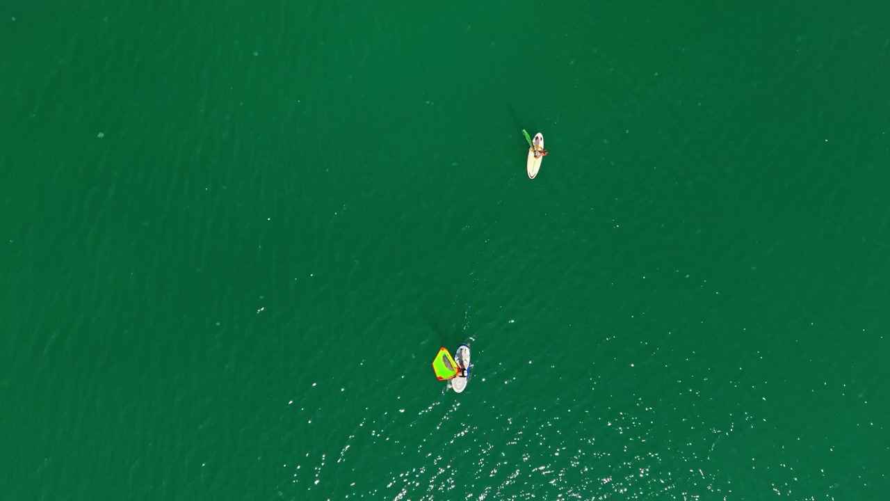 Due persone fanno paddleboard in uno specchio d'acqua verde in una giornata di sole con cieli sereni