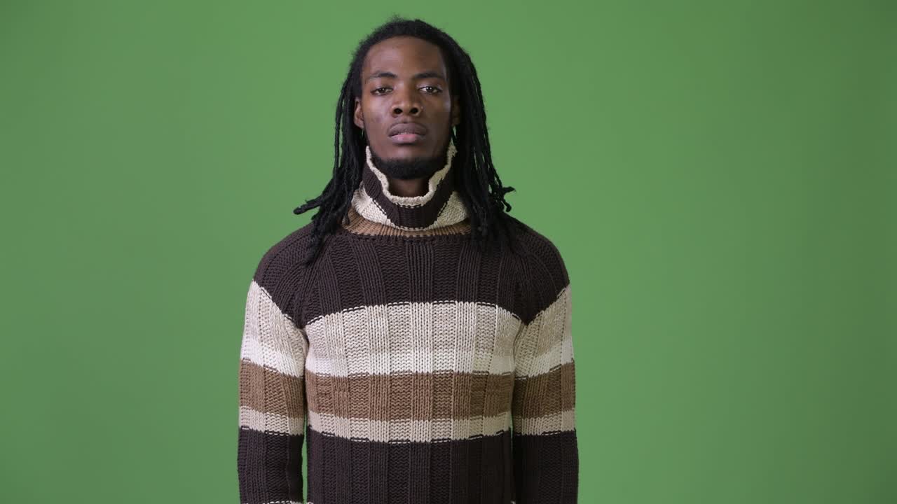 Giovane e affascinante uomo africano con i dreadlock su sfondo verde
