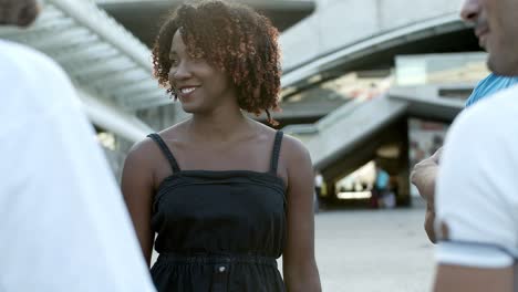 front view of smiling curly lady standing on street and communicating