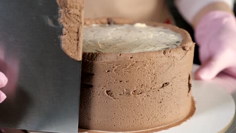 pastry chef woman is smearing chocolate cream on sponge cake