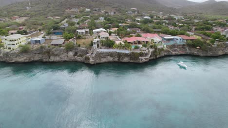 Aerial-trucking-shot-of-the-small-town-in-the-Caribbean-with-clear-emerald-waters