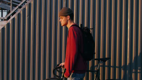 young man walking with bicycle at sunset