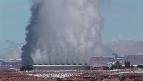 mediumshot of a factory in the arizona desert emitting clouds of smoke