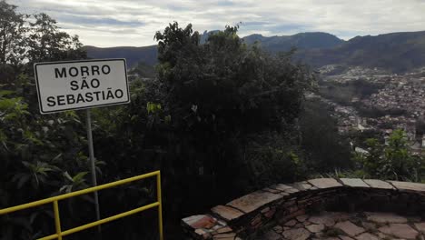 sign of the saint sebastian hill viewpoint of ouro preto with itacolomi mountain peak in the background slowly panning around seeing a bit of the historic city below. translation: 'san sebastian hill'