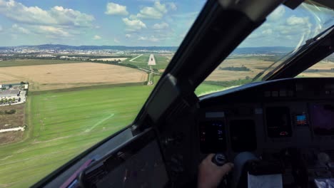 an immersive pilot’s perspective in a real time approach to bratislava airport runway, surrounded by green fields, under a blue sky with sacattered clouds