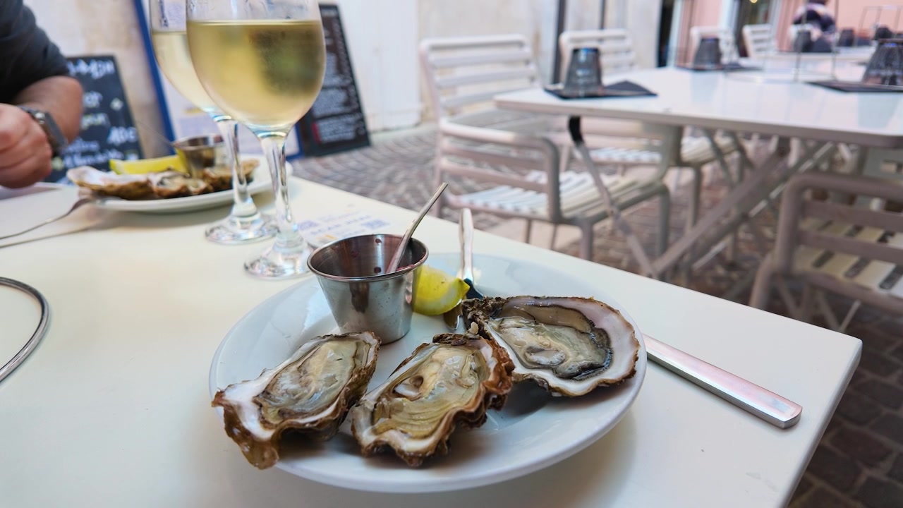 Nahaufnahme von frischen Austern, Zitrone und Mignonette-Sauce auf einem Tisch in einem Außenrestaurant.