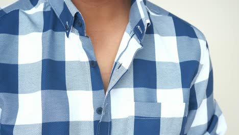 man buttoning up a plaid shirt