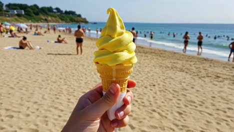 enjoying a delicious yellow soft serve ice cream on a sunny beach with people swimming and relaxing in the background