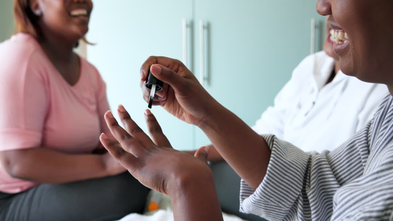 Painting nails, African American women laughing, spending time together at home