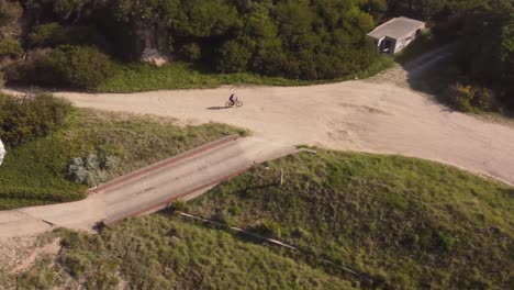 Aerial-view-of-Bicycle-driving-on-rural-off-road-Route-during-sunny-day-in-Chapadmalal,Buenos-Aires-Argentina