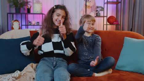 two young girls smiling and giving thumbs up