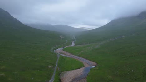 Pan-up-shot-reveals-car-passing-down-winding-road