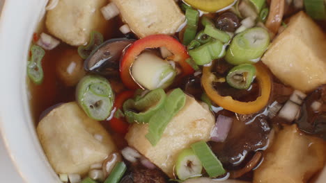 closeup of a miso and tofu soup dish, loaded with color and flavor