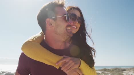 feliz pareja caucásica abrazada cerca de la playa buggy por el mar