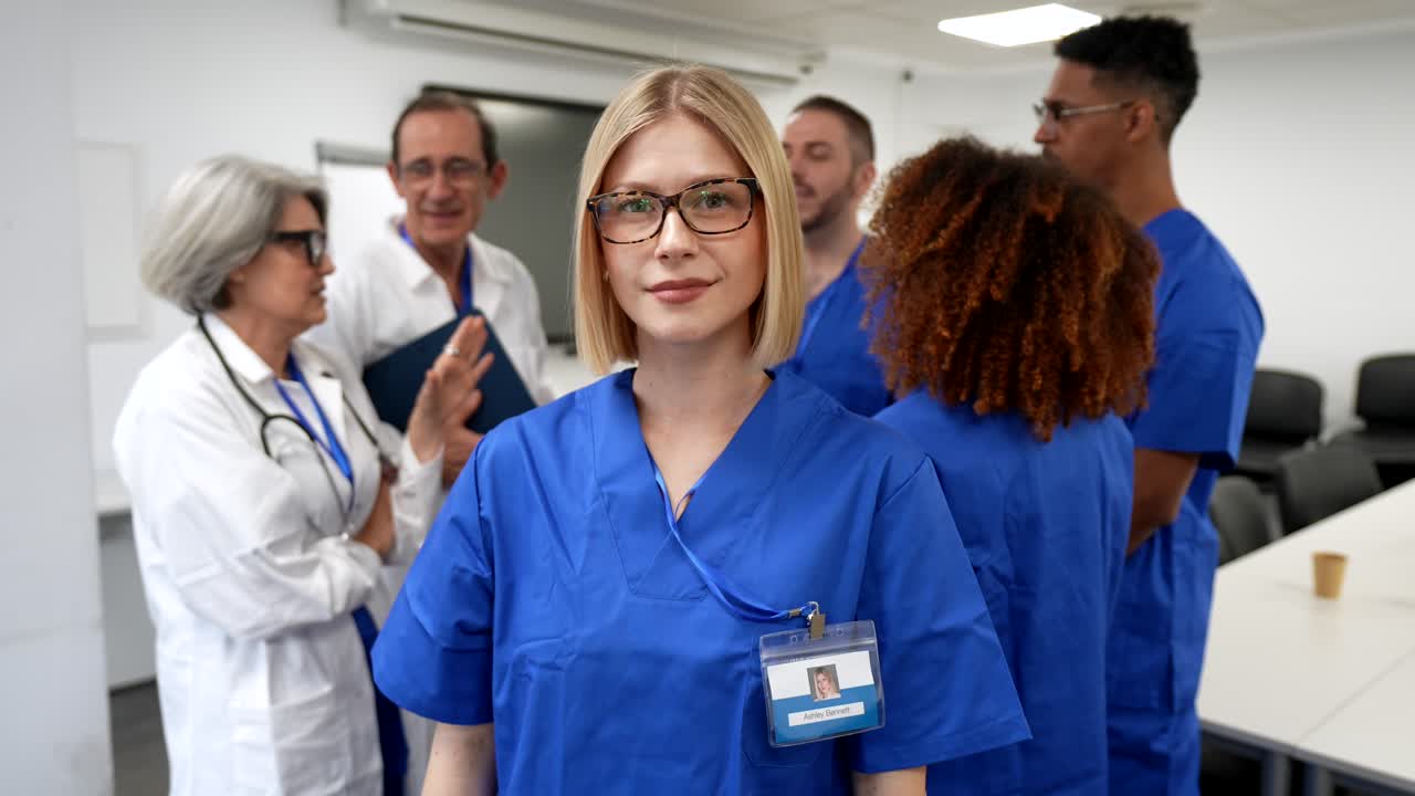 Giovane infermiera sicura di sé in divisa medica con l'équipe medica
