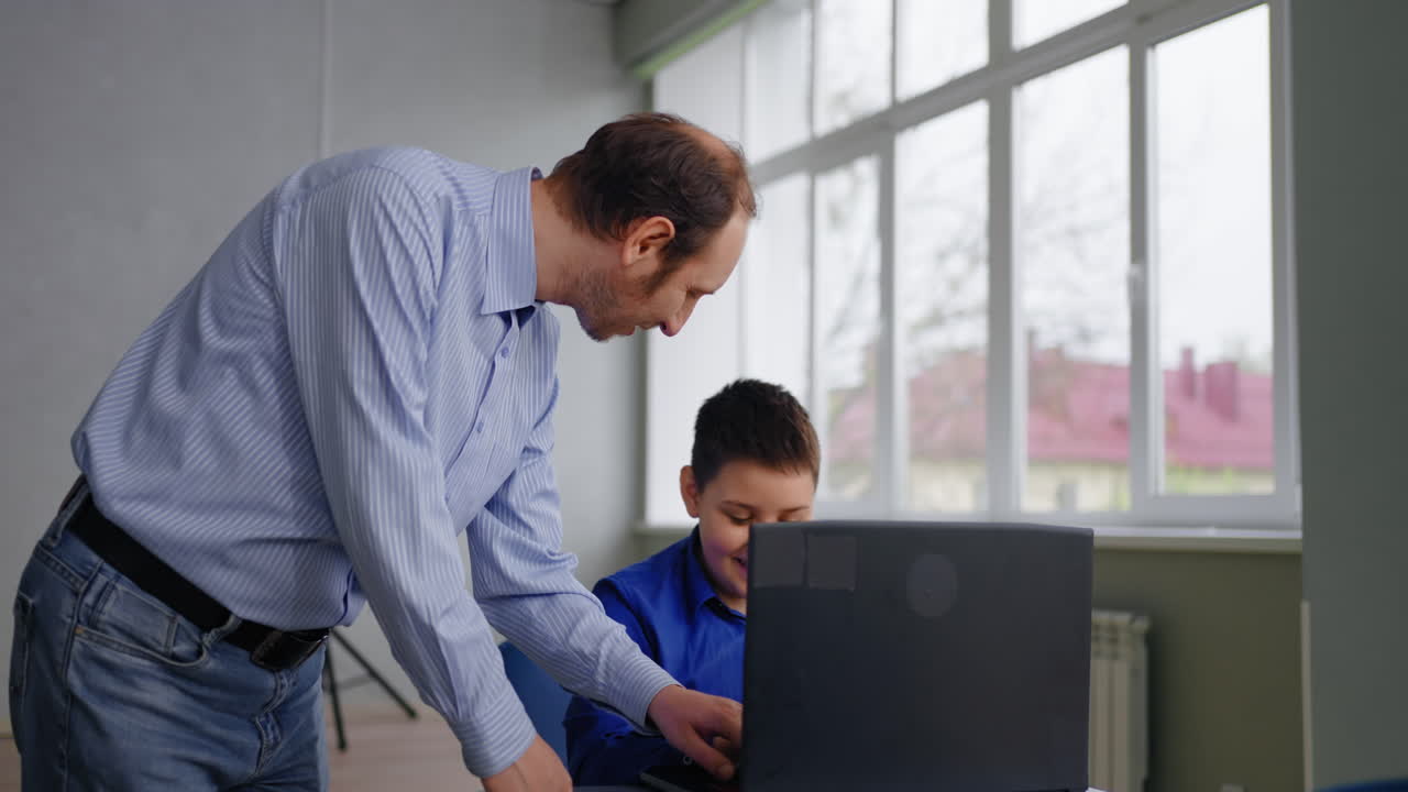 maestro ayudando al estudiante con una computadora portátil en el aula