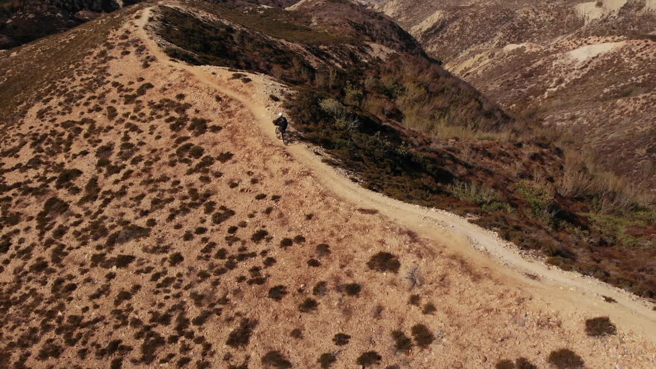 hombre montando bicicleta en la montaña con traje negro cerca de la playa