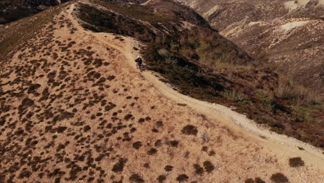 Man-riding-bike-in-the-mountain-with-black-outfit-near-the-beach