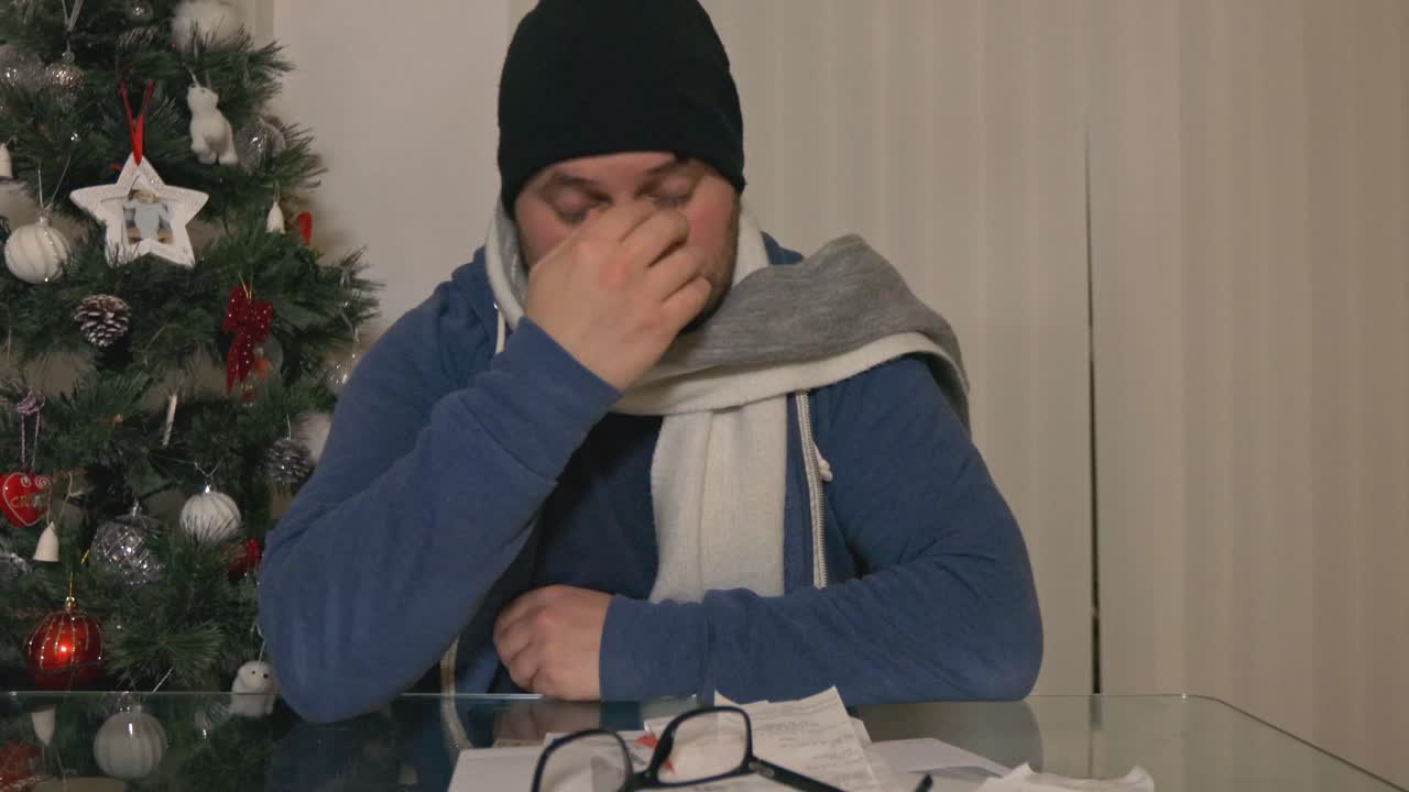 안경을 쓴 차가운 좌절된 남자는 크리스마스에 영수증 서류 더미를 화나게 했다