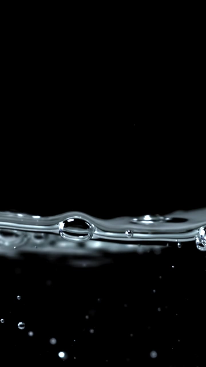 Slowmotion nærbillede af vandoverflade med bobler på sort baggrund
