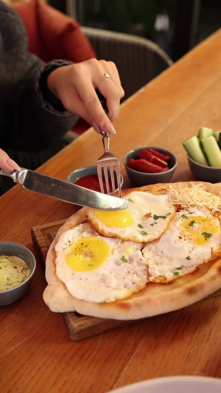 Woman eating khachapuri with fried eggs