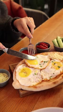 mujer comiendo khachapuri con huevos fritos