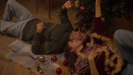 couple relaxing and decorating christmas tree