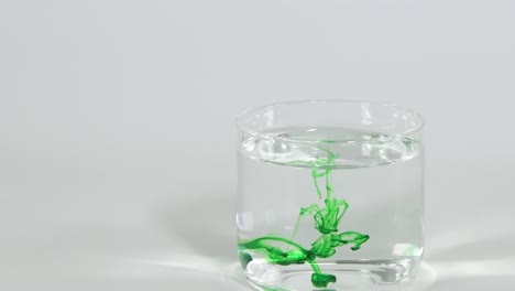 green dye forms intricate patterns as it diffuses in a clear glass of water.