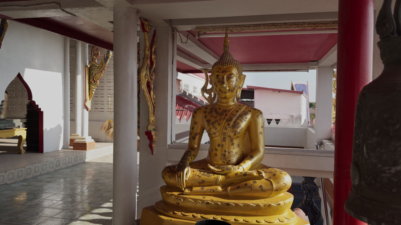 Golden Buddha statue revealed behind bell in Thai temple. Slow motion slider shot with spiritual atmosphere, Buddhism concept, travel and religion in Thailand.