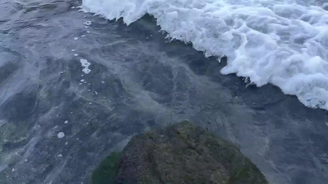 Чистая океанская вода с нежными волнами, омывающими подводный камень.