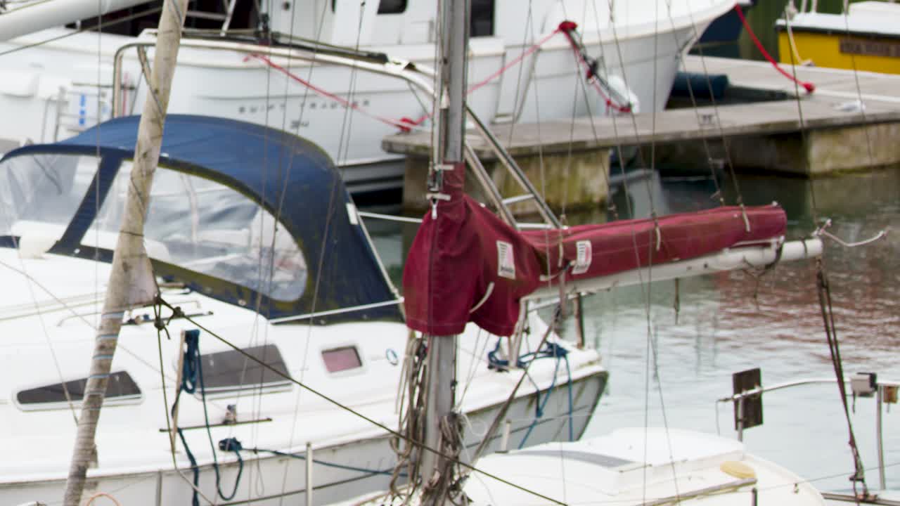 Camera slowly pans across docked sailboats and yachts in Dundee marina, overcast daylight, steady shot