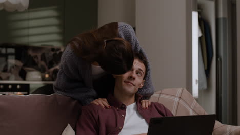 couple relaxing on sofa, working on laptop