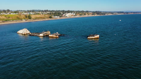 Aerial-view-around-a-shipwreck-on-the-coast-of-Rio-del-Mar,-sunny-California,-USA