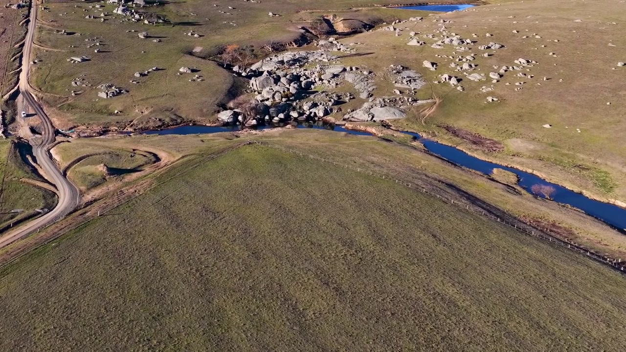 Ripresa aerea con drone ad alta angolazione di una strada sterrata tortuosa e massi di granito a Uralla, Australia.