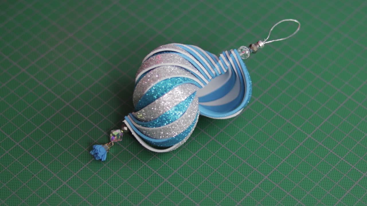 adorno navideño de foami con purpurina azul y plateada sobre tapete de corte verde