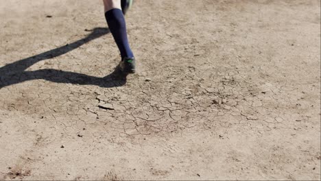 close shot of a football soccer player kicking the leather ball on dry dirt floor