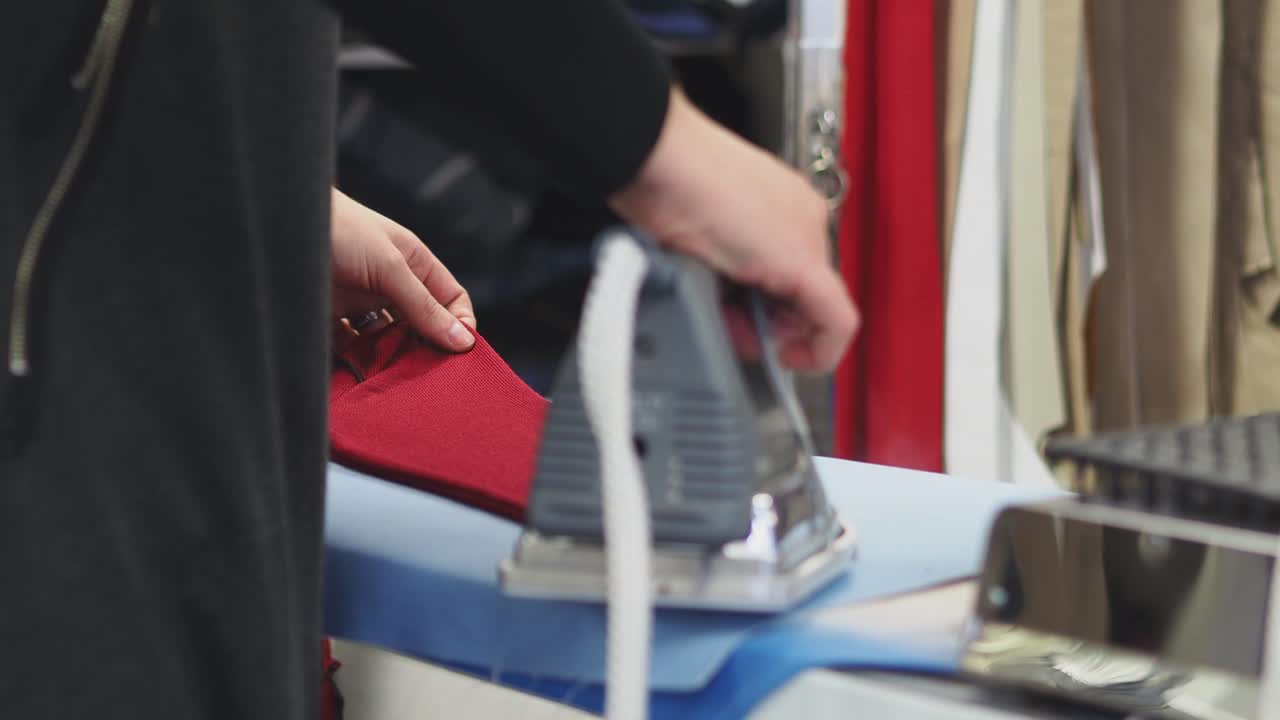 A woman ironing a red dress