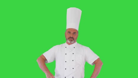 cocinero serio con los brazos cruzados mirando a la cámara en una pantalla verde, llave de croma