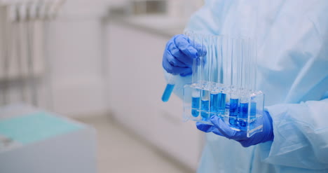 Working-In-Lab-Scientist-Holding-Test-Tubes-And-Analyzing-Liquid