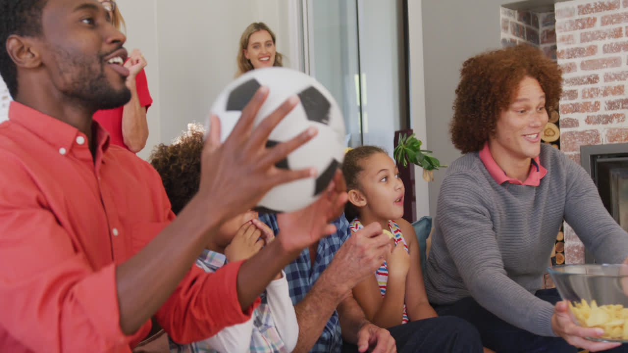 소파 에 앉아서 축구 경기를 시청 하는 다양한 가족 의 비디오