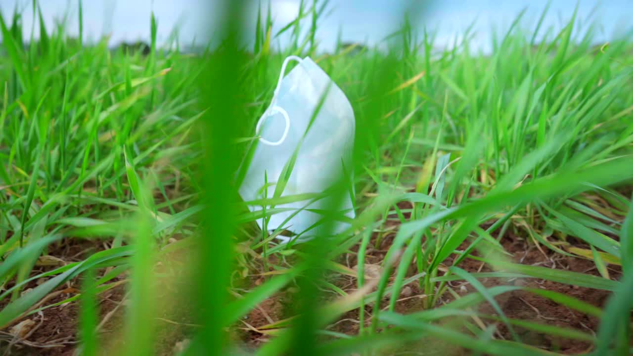 코로나 바이러스 covid-19 전염병 동안 강한 바람, 자연 오염에 의해 푸른 잔디에 버려진 의료 보호 얼굴 마스크