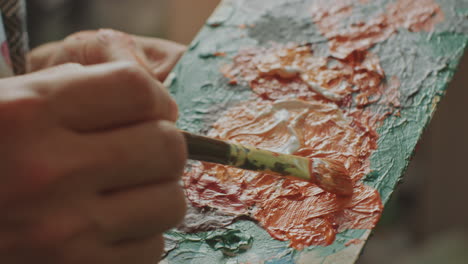 hands of artist mixing paint colors on palette with brush