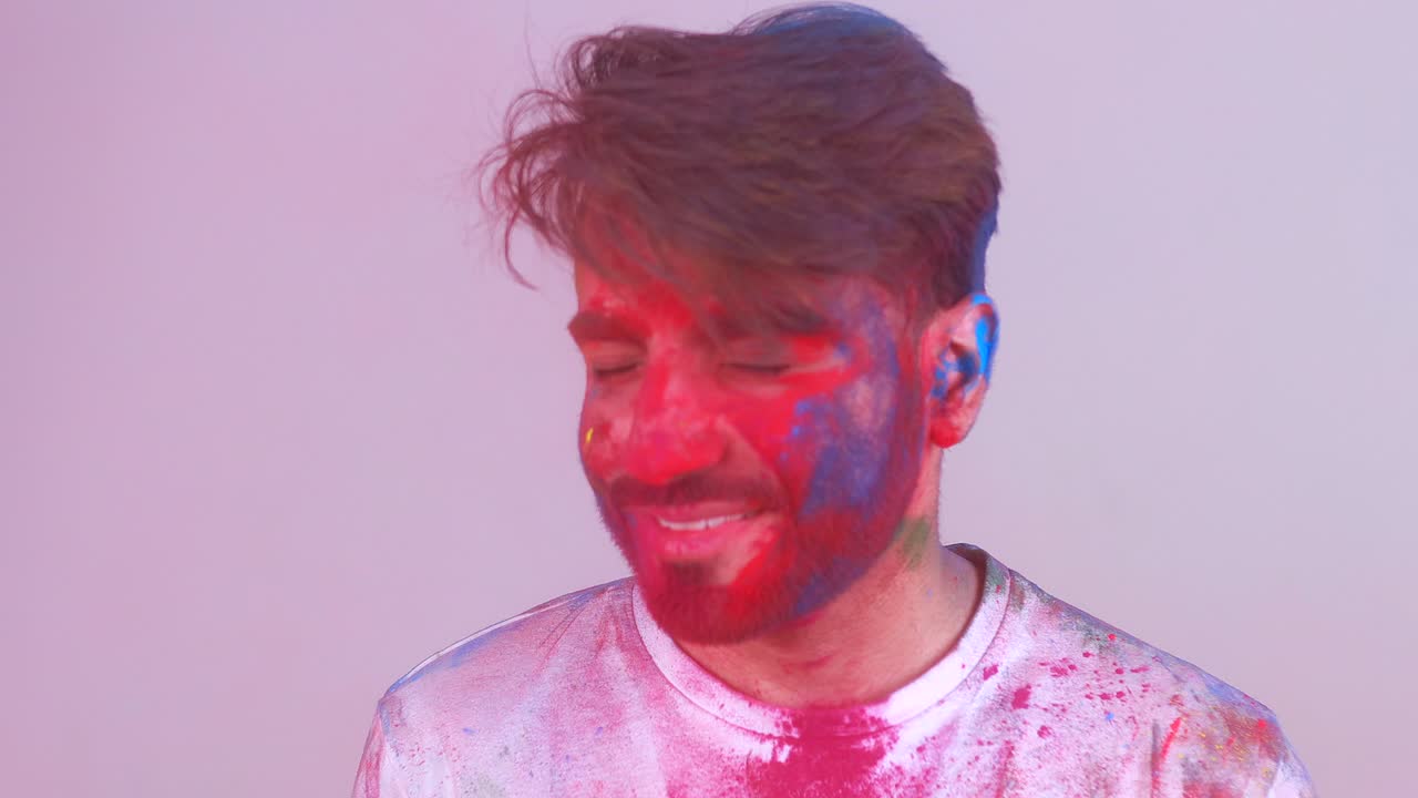 bellissimo studente indiano dipinto a colori che celebra il festival di holi in studio sullo sfondo bianco isolato