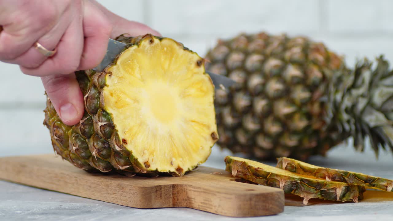 칼을 들고 있는 남성의 손은 파인애플의 둥근 조각을 잘라냈습니다.