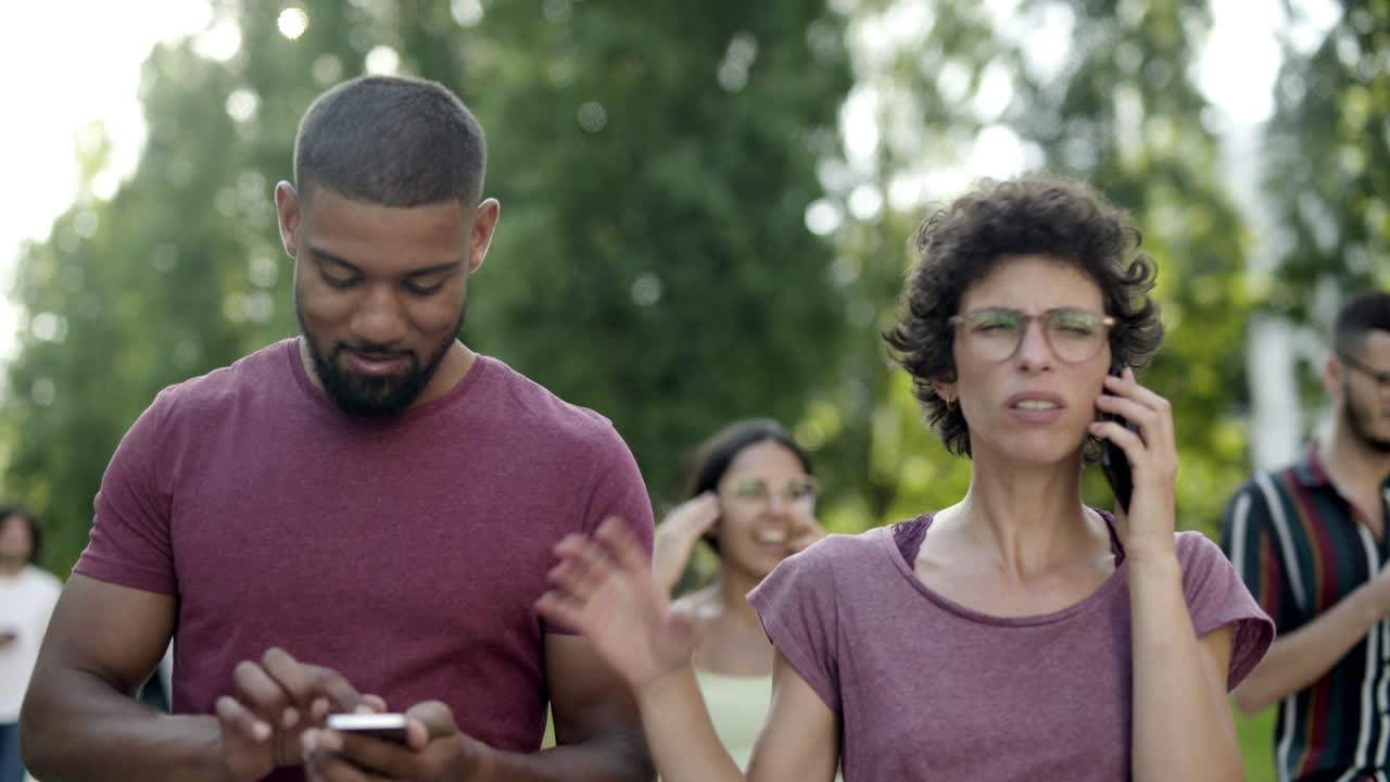 Smiling curly woman in eyeglasses talking on smartphone